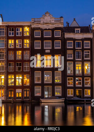 Historische Gebäude am Damrak Kanal in der Mitte des wunderschönen Amsterdam bei Nacht. Ligts der Gebäude sind in den Kanal wider. Stockfoto