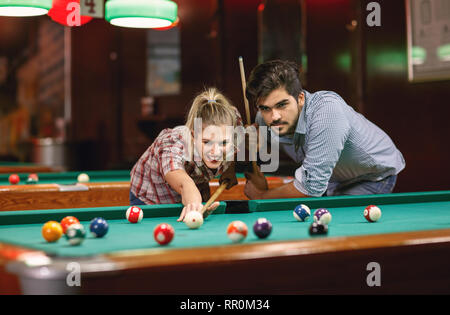 Spielen Sie Billard- Ein junges Paar Shooting Pool Ball Stockfoto