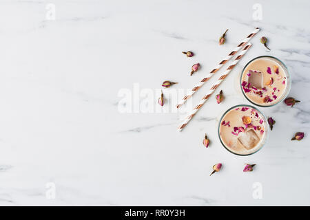 Eiskaffee mit Rose und Kardamom in ein hohes Glas mit getrockneten Rosen und Strohhalme auf weißem Hintergrund umgeben. Ansicht von oben mit der Kopie Platz für Text. Stockfoto