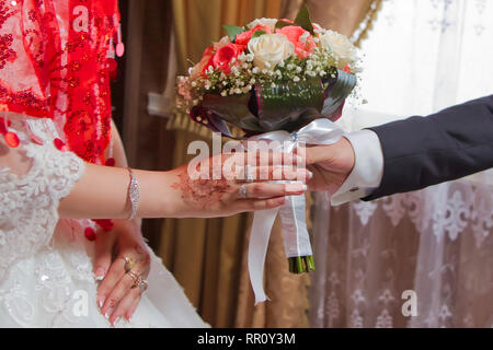 Die Männer gibt Blumen für die Braut. Hände mit Hochzeit Blumen, Bräutigam setzt auf einer Hochzeit Blumen an die Braut, eine Hochzeit Blumen, Pflegen Stockfoto