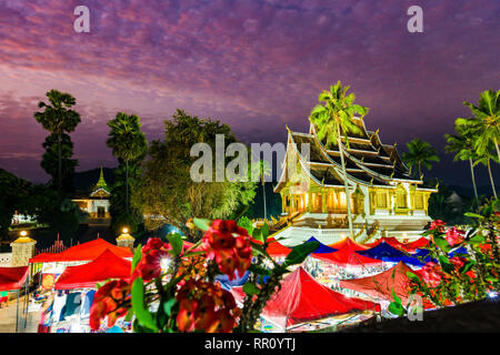 Atemberaubende Aussicht auf die schöne Haw Pha Bang Tempel bei Sonnenuntergang mit der beleuchteten Nacht Markt Vorhänge in den Vordergrund. Stockfoto