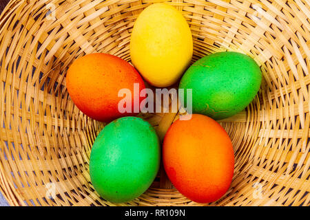 Fünf bunte Ostereier in einem Strohkorb isoliert Stockfoto