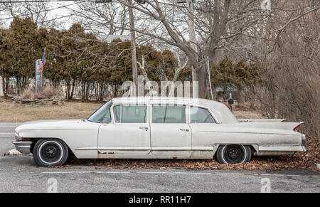 Seitenansicht einer alten weißen aufgegeben Cadillac sitzen auf einem Parkplatz Stockfoto