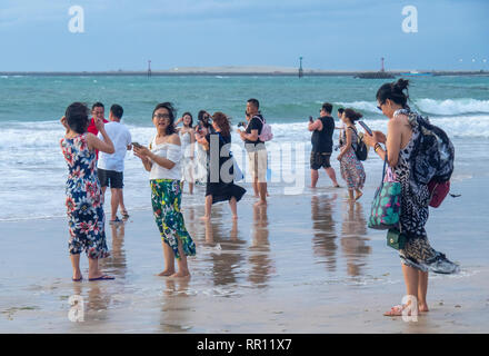 Chinesische Touristen im Urlaub Urlaub am Strand bei Sonnenuntergang in der Bucht von Jimbaran Bali Indonesien Stockfoto