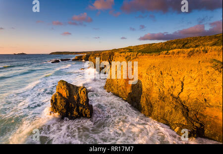 Dramatischer Sonnenuntergang Licht erhellt die Klippen am Gwithian Cornwall England Großbritannien mit godrevy Island am Horizont. Stockfoto