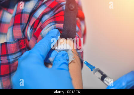 Close-up Hände Arzt oder Pflegepersonal Impfung mit der Spritze zu Patienten injiziert Oberarm für behandelt. Arzt, eine Injektion zu einem Patienten Stockfoto