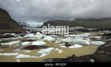 Svinafellsjokull Gletschersee mit schwimmende Eisberge mit Gletscher und Berge im Hintergrund und bedecktem Himmel in Vatnajökull National Park, Süd Stockfoto