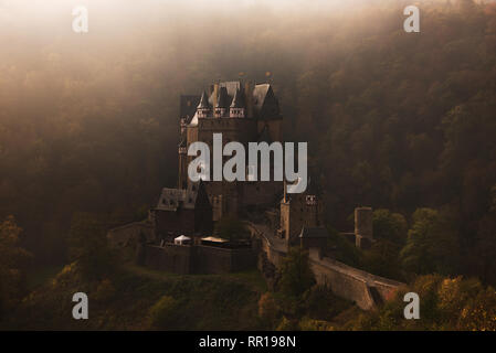 Die mittelalterliche Burg Eltz Burg, die auf einem Felsen in einem Wald im Herbst Farben von morgen Nebel in der Nähe von Mosel in Wierschem, Deutschland umgeben. Stockfoto