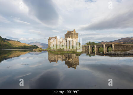 Historische Eilean Donan Castle am frühen Morgen Licht mit großen Wolken im Himmel und mit dem Spiegelbild im Wasser in der Nähe von Skye in Schottland, Großbritannien. Stockfoto