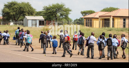 Masse der Grundschüler zu Fuß von der Schule nach Hause am Nachmittag in ihren Schuluniformen in der North West Provinz, Südafrika gekleidet Stockfoto