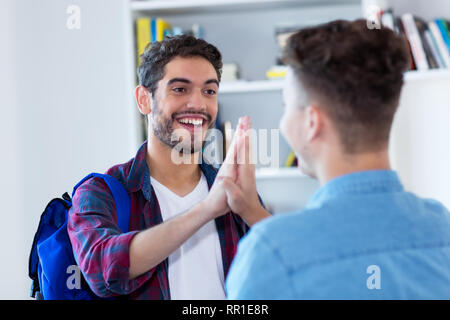 Zwei männliche Studenten hoch fünf an der Bibliothek der Schule Stockfoto