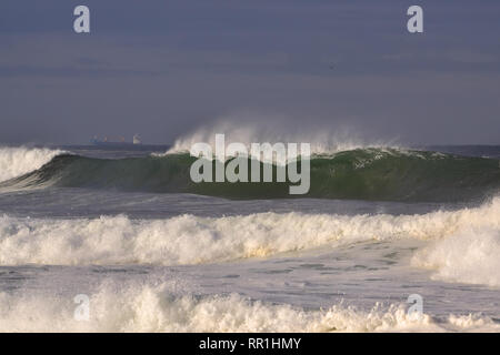 Ocean Wave sehen Spray durch Wind und Schiffe, die in den Horizont, die in der portugiesischen Küste in einem Herbst schöner Morgen Stockfoto