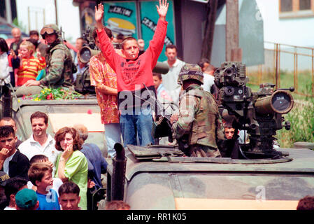 1999 - Ethenic Albaner versammeln sich in den Straßen für eine Parade statt die amerikanischen Streitkräfte im Kosovo Dorf Koretin zu ehren. Kinder Klettern Sie auf die Oberseite eines M998 High-Mobility Multipurpose Radfahrzeug (Hmmwv) mit TOW Missile. Stockfoto