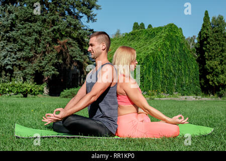 Gesunde Lebensweise. Paar Üben Yoga im Freien auf Mat zurück zu zurück zu meditieren freudige Stockfoto