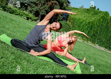 Gesunde Lebensweise. Paar Üben Yoga im Freien sitzen, biegen an der Seite glücklich Stockfoto