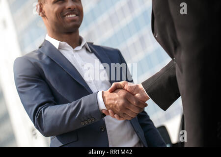 Junger Mann und Business Partner stehen in der Nähe von Auto Händeschütteln freudige close-up Stockfoto