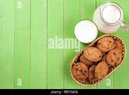 Kanne und Glas Milch mit Haferflocken Cookies auf einer grünen Holz- Hintergrund mit Kopie Platz für Ihren Text. Ansicht von oben Stockfoto