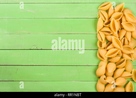 Rohe pasta Muscheln auf einer grünen Holz- Hintergrund mit Kopie Platz für Ihren Text. Ansicht von oben Stockfoto