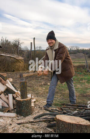 Man Holzhacken im Dorf Stockfoto