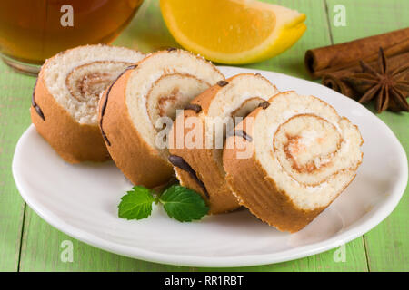 Keks schweizer Rolle mit einer Tasse Tee auf Grün Holz- Hintergrund Stockfoto