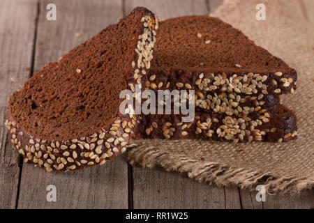Scheiben Schwarzbrot mit Sesam seedson auf dem alten Holz- Hintergrund Stockfoto