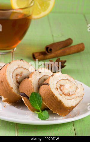 Keks schweizer Rolle mit einer Tasse Tee auf Grün Holz- Hintergrund Stockfoto