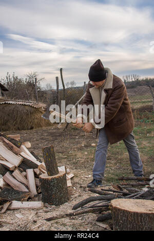 Man Holzhacken im Dorf Stockfoto