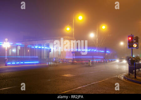 Southport, Merseyside. Februar 2019. Wetter in Großbritannien. Trübe, nebelige, nebelige beginnen Sie den Tag mit leichtem Nieseln, wenn der Verkehr im Stadtzentrum am frühen Morgen die feuchten Gehwege beleuchtet. Die blauen Lichter des Rettungswagens, die am Notfahrzeug vorbeifahren, hinterlassen Reflexionen auf der Fahrbahn. Stockfoto