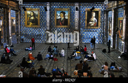 23. Februar 2019, Sachsen, Leipzig: Am Kunstkraftwerk, Besucher der Multimedia Show "LEONARDO DA VINCI, Raffael, Michelangelo, Riesen der Renaissance" der da Vinci Gemälde "Mona Lisa", "Portrait eines jungen Mannes" und "Dame mit dem Hermelin" (L-R), die auf den Mauern der ehemaligen Maschinenhalle, die bis zu acht Meter hohen projiziert werden. Die außergewöhnliche Multimedia Projektion der italienischen Immersive Kunst Fabrik, die anlässlich des 500. Geburtstags von Leonardo da Vincis Tod gezeigt werden wird, wurde bereits von über 8000 Besucher seit der Eröffnung auf gesehen worden Stockfoto