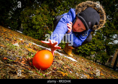 Junge Suchen und Aufnehmen und Ostereier aus dem Boden Stockfoto