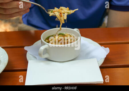 Closeup junger Mann heiße Suppe essen im Biergarten oder im Restaurant Stockfoto