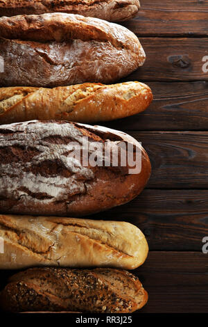 Sortiment von gebackenem Brot und Brötchen auf hölzernen Tisch Hintergrund. Bäckerei poster Konzept Stockfoto
