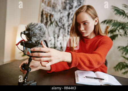 Ich bin fast fertig... Porträt von Ernst weibliche Blogger einrichten Ihr Stativ montiert Digitalkamera, bevor Sie ein neues Video für Vlog. Social Media. Stockfoto