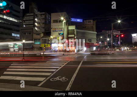 Leichte Spuren von vorbeifahrenden Autos auf einer belebten Straße in Hiroshima, Japan, bei Nacht Stockfoto