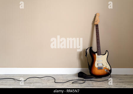 Elektro Gitarre mit Kabel an der Wand im Hintergrund. Musik instrument Konzept Stockfoto