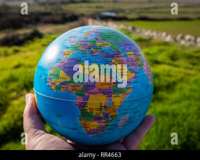 Eine Frau mit einem Ball der Welt oder den Planeten Erde in seiner Hand. Ökologiekonzept Stockfoto