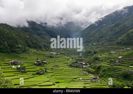 Philippinen, Ifugao Provinz, Kordilleren, Banaue, Hunduan, Reisanbau auf hapao Reisterrassen in Berge, grüne Reisfelder und Hapao Kirche vor der Berge mit Wolken Stockfoto