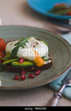 Sandwich mit Avocado, pochierte Eier, Rucola und Tomaten Stockfoto