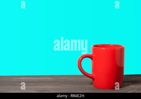 Red Cup auf einer hölzernen Oberfläche auf einem blauen Hintergrund Stockfoto