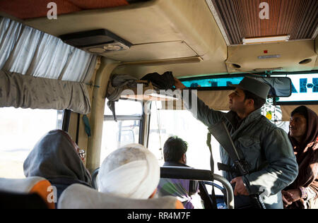 Herat, Afghanistan. 24 Feb, 2019. Ein afghanischer Polizist sucht einen Bus an ein Security Checkpoint entlang Herat-Farah Hauptstraße in Herat, Afghanistan, 24.02.2019. Die afghanischen Sicherheitskräfte neun Taliban Kämpfer getötet haben und beschlagnahmt fast 900 kg Suchtstoffen während separate Arbeitsgänge, das Afghanische Ministerium für Inneres sagte Samstag. In der Provinz Herat, der afghanischen nationalen Polizei (ANP) ergriff mehr als 570 kg von Betäubungsmitteln und Opium und ein Fahrzeug nach dem ANP legte einen Hinterhalt und engagierte sich mit Drogenhändlern an einer Hauptstraße. Credit: Elaha Sahel/Xinhua/Alamy leben Nachrichten Stockfoto