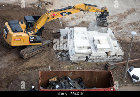 Schwerin, Deutschland. 19 Feb, 2019. Ein Bagger wird verwendet, um die demontierten Betonwände des leeren Hochhäuser im Stadtteil Neu Zippendorf zu sortieren. Das elfstöckige Gebäude sind 36 Meter hoch und werden nun durch Stock zerlegt. Insgesamt 23.000 Tonnen Bauschutt sind für den Rückbau der beiden Hochhäuser erwartet. Credit: Jens Büttner/dpa-Zentralbild/ZB/dpa/Alamy leben Nachrichten Stockfoto