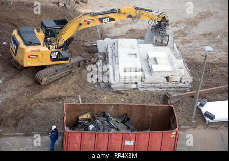 Schwerin, Deutschland. 19 Feb, 2019. Ein Bagger wird verwendet, um die demontierten Betonwände des leeren Hochhäuser im Stadtteil Neu Zippendorf zu sortieren. Das elfstöckige Gebäude sind 36 Meter hoch und werden nun durch Stock zerlegt. Insgesamt 23.000 Tonnen Bauschutt sind für den Rückbau der beiden Hochhäuser erwartet. Credit: Jens Büttner/dpa-Zentralbild/ZB/dpa/Alamy leben Nachrichten Stockfoto