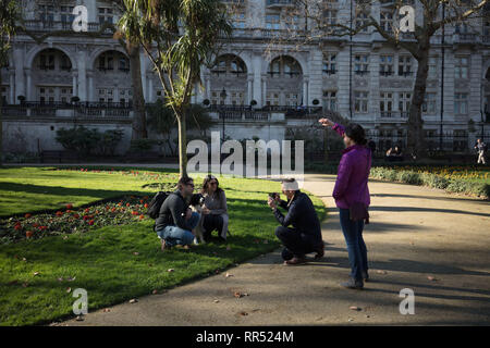 London, Großbritannien. 24. Februar, 2019. Londoner nimmt ein Bild von zwei Touristen zusammen mit seinem Hund in Whitehall Gardens, Westminster, am frühen Nachmittag an diesem sonnigen, Februar Frühling wie Tag. Credit: Joe Kuis/Alamy leben Nachrichten Stockfoto