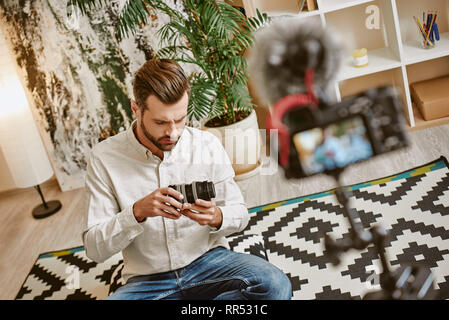 Die Erstellung von Inhalten. Junge Bartgeier blogger Halten der Kamera während der Aufnahme neuer video Episode für seine Vlog. Social Media. Instagram Stockfoto
