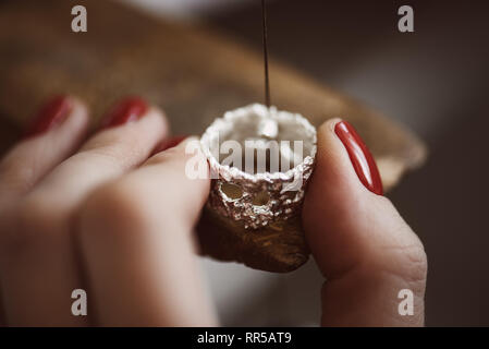 Zarte Schmuck arbeiten. Nahaufnahme von der Hand eines weiblichen Juwelier arbeiten an einem Ring Größe an ihrer Werkbank. Schmuck. Business. Schmuck arbeiten Stockfoto