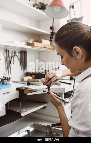 Ich bin beschäftigt. Seitenansicht der weiblichen Juwelier Vorbereiten der Werkzeuge für die Herstellung von Schmuck an ihrem Schmuck Werkstatt. Business. Schmuck Werkstatt. Schmuck equi Stockfoto