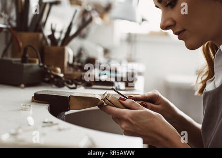 Ich habe meine Inspiration. Seitenansicht eines weiblichen aufgeregt Juwelier erstellen einen silbernen Ring an ihrer Werkbank. Und Zubehör. Schmuck. Juwel Stockfoto