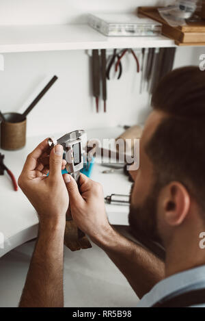 Ar in Details. Nahaufnahme Foto eines jungen männlichen Juwelier messen Ring mit einem Werkzeug in der Werkstatt. Schmuck Herstellung Konzept. Schmuck Werkstatt. Stockfoto