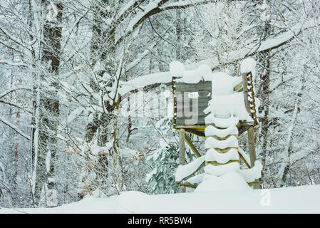 Einfache Holz- Jagd im Schnee bedeckt. Jagd Hirsch blind neben einer Reihe von Bäumen im Winter Landschaft Stockfoto
