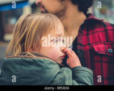 Ein kleines Kind wird in einer Schlinge im Freien, der von seinem Vater durchgeführt Stockfoto